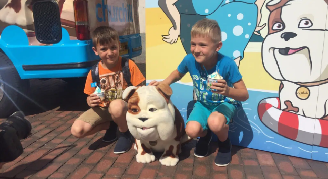 Two kids with ice cream petting a model of Churchill the dog.