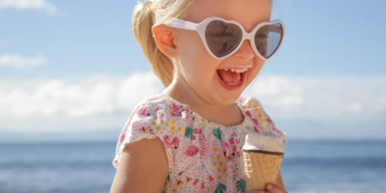 A kid smiling and holding an ice cream.