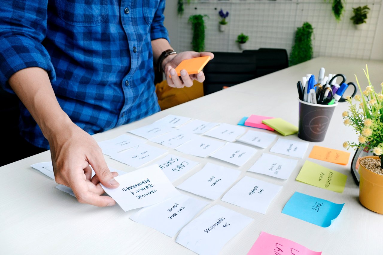 An individual carefully positioning sticky notes on a table, organizing thoughts or tasks in a visually striking manner.
